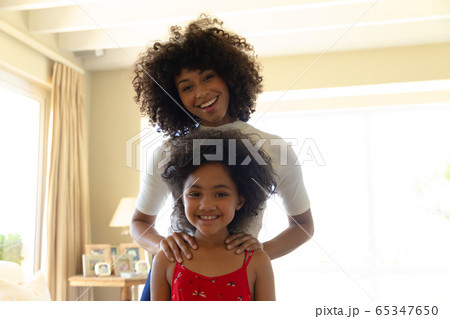 Mixed race woman with her young daughter smiling at camera Mixed race woman with her young daughter smiling at camera 65347650
