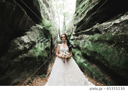 Portrait of stunning bride with long hair posing with great bouquet 65355230