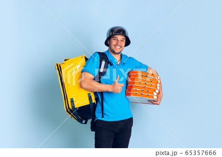 Contacless delivery service during quarantine. Man delivers food and shopping bags during insulation. Emotions of deliveryman isolated on blue background. 65357666