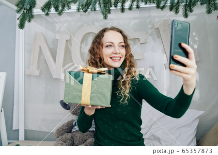 Charming woman photographing with gift 65357873