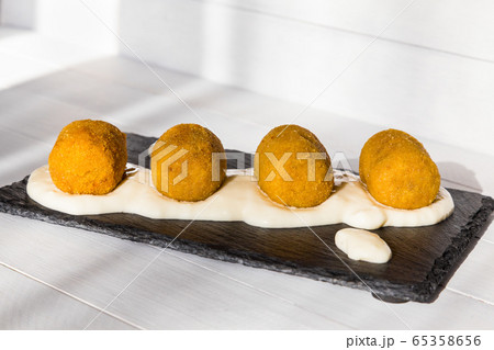 Fried vegetable croquettes with white sauce on black stone plate on wooden background. Unhealthy food. Side view 65358656