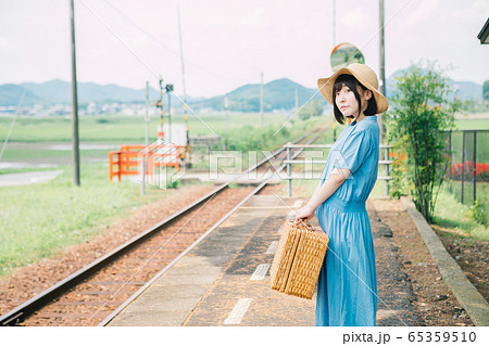 田舎の駅で電車を待つ女性の写真素材