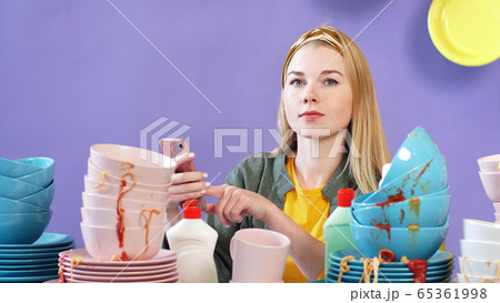 Attractive woman thought about how to wash a mountain, a pile of dirty dishes, an isolated background Attractive woman thought about how to wash a mountain, a pile of dirty dishes, an isolated background 65361998