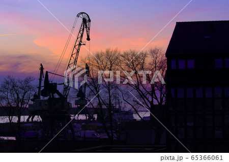 Silhouettes of port crane, trees and building in beautiful sunset in port harbor in Klaipeda, Lithuania. 65366061