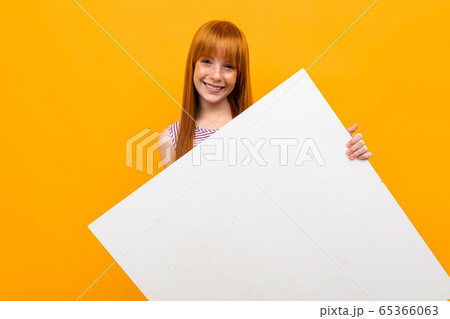 Beautiful caucasian woman with red hair works with big white plate isolated on yellow background Beautiful caucasian woman with red hair works with big white plate isolated on yellow background 65366063