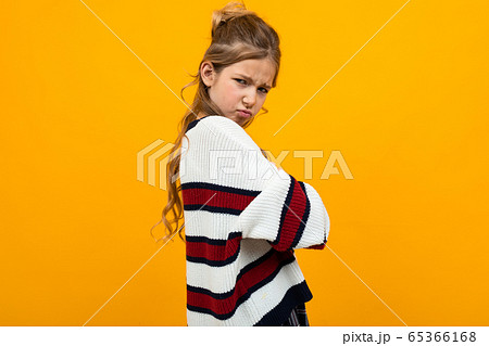 offended sad teenager girl in a striped sweater with arms crossed on an orange background with copy offended sad teenager girl in a striped sweater with arms crossed on an orange background with copy 65366168