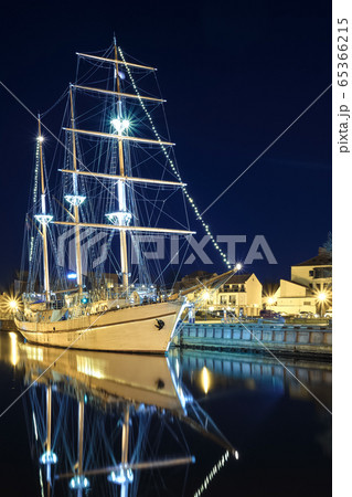 Sailing boat anchored amd moored in old town of Klaipeda, Lithuania, with evening lights on. Medieval town and barquentine reflection in calm waters. Sailing boat anchored amd moored in old town of Klaipeda, Lithuania, with evening lights on. Medieval town and barquentine reflection in calm waters. 65366215