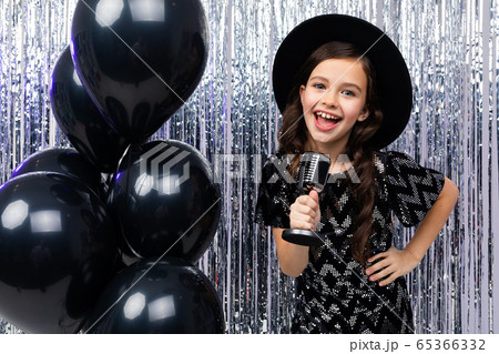 portrait of a young singer in a black dress with a microphone in her hands on a shiny background portrait of a young singer in a black dress with a microphone in her hands on a shiny background 65366332