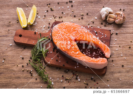 Raw salmon steak on wooden board top view. Healthy food, diet and mediterranean cuisine concept Raw salmon steak on wooden board top view. Healthy food, diet and mediterranean cuisine concept 65366697