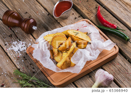 Baked potato wedges with herbs and ketchup decorated with dill. Baked potato wedges with herbs and ketchup decorated with dill. 65366940