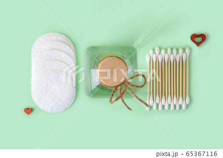 Cleansing lotion or tonic in a glass jar, cotton pads and cotton buds wood stick on a pastel mint Cleansing lotion or tonic in a glass jar, cotton pads and cotton buds wood stick on a pastel mint 65367116