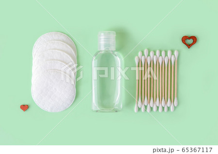 Cleansing lotion or tonic in a transparent jar, cotton pads and cotton buds on a pastel mint Cleansing lotion or tonic in a transparent jar, cotton pads and cotton buds on a pastel mint 65367117