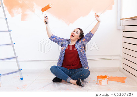 Happy smiling woman painting interior wall of new house. Redecoration, renovation, apartment repair and refreshment concept. 65367807