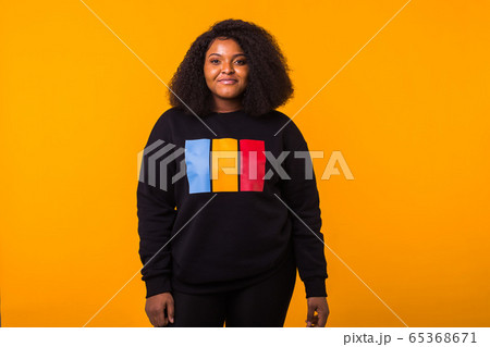Young beautiful african american girl with an afro hairstyle. Portrait on yellow background with copy space. Girl looking at camera. Young beautiful african american girl with an afro hairstyle. Portrait on yellow background with copy space. Girl looking at camera. 65368671
