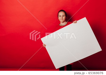 Schoolgirl's girl holds sign for inscriptions on red background 65369076