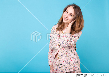 Smiling young girl in pajamas home wear posing while resting at home isolated on blue background studio portrait. Relax good mood lifestyle concept. Smiling young girl in pajamas home wear posing while resting at home isolated on blue background studio portrait. Relax good mood lifestyle concept. 65369740