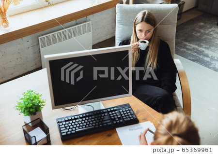 Young woman sitting in office during the job interview with female employee, boss or HR-manager, talking, thinking, looks confident 65369961