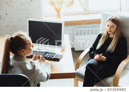 Young woman sitting in office during the job interview with female employee, boss or HR-manager, talking, thinking, looks confident Young woman sitting in office during the job interview with female employee, boss or HR-manager, talking, thinking, looks confident 65369980