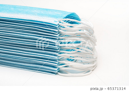 Stack blue surgical medical face masks with rubber ear straps on white background. Close-up view, forced perspective Stack blue surgical medical face masks with rubber ear straps on white background. Close-up view, forced perspective 65371314