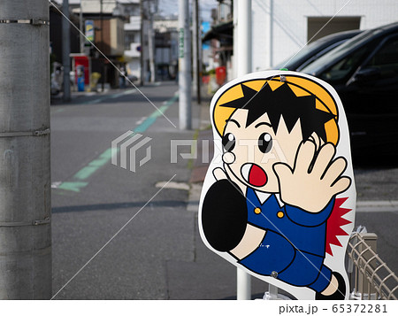 交通量の多い住宅街に置かれている飛び出し坊やの看板 65372281