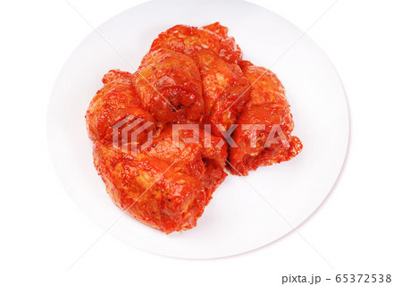 Uncooked marinated chicken thigh. Chicken legs in a red marinade on a white plate .Isolated Uncooked marinated chicken thigh. Chicken legs in a red marinade on a white plate .Isolated 65372538