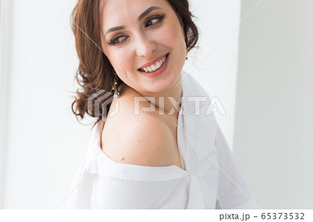 Close-up of fashion shoot of young brunette woman with elegant hairstyle in white studio. Trendy style concept. Close-up of fashion shoot of young brunette woman with elegant hairstyle in white studio. Trendy style concept. 65373532