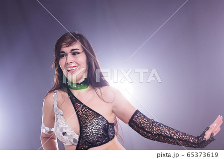 Young woman belly dancer in exotic dress with gold, dancing tribal fusion dance in studio. 65373619