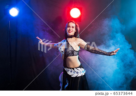 Young woman dancing in Tribal Fusion style. Belly dance on the stage. Young woman dancing in Tribal Fusion style. Belly dance on the stage. 65373644