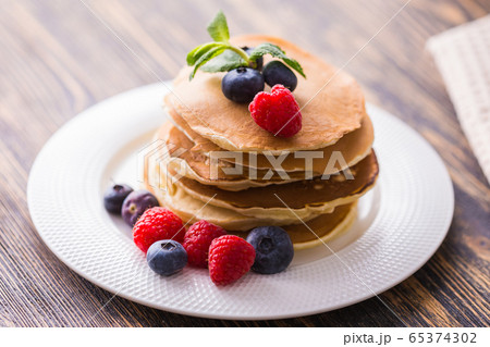 Pancakes with blueberries and raspberry on wooden background. Breakfast and traditional meal. 65374302