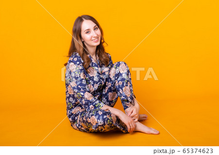 Excited young woman in home wear, widely smiling having fun. Isolated on yellow background. Excited young woman in home wear, widely smiling having fun. Isolated on yellow background. 65374623