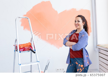 Lovely woman painting wall. Renovation, redecoration and repair concept. 65375007