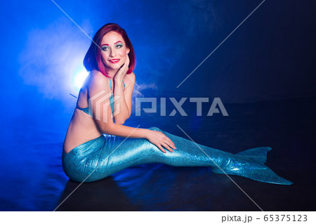 Mermaid with red hair resting on blue background. Fantasy concept. Mermaid with red hair resting on blue background. Fantasy concept. 65375123