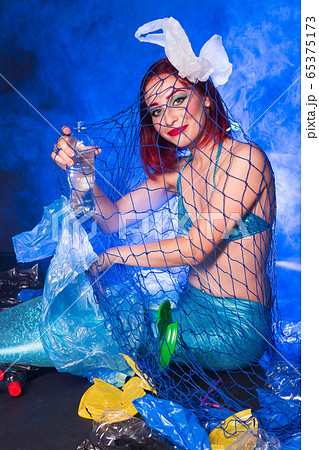 Fantasy stupid mermaid in deep ocean. Plastic water bottles and