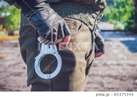 Handcuffs on the belt of a policeman who is preparing to pull them out and apply 65375343
