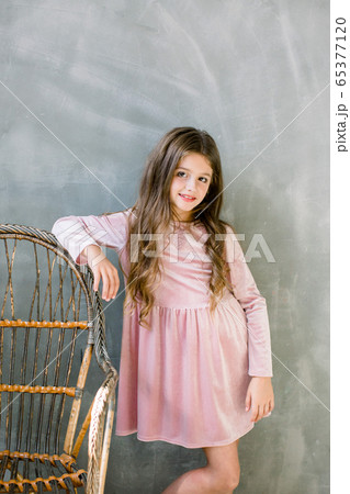 Cute baby girl 5-6 year old wearing stylish pink dress overgrey background. Looking at camera. Birthday party. Celebration. Cute baby girl 5-6 year old wearing stylish pink dress overgrey background. Looking at camera. Birthday party. Celebration. 65377120