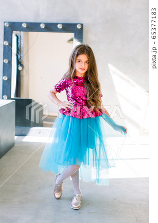 Little girl with long Brown hair dancing, smling and having fun over grey loft wall background. Five years old female child posing. 65377183