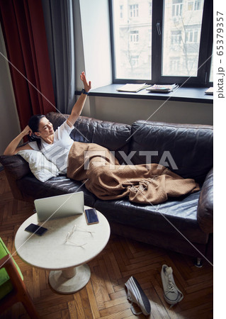 Relaxed girl stretching herself in her cozy apartment Relaxed girl stretching herself in her cozy apartment 65379357