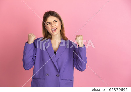 Caucasian young woman's portrait on pink studio background, emotional and expressive 65379695