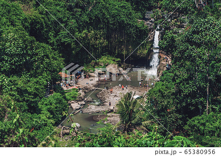 large waterfall in rocks with palm trees 65380956
