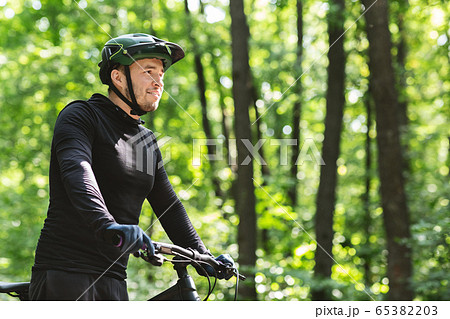 Young man cyclist enjoying riding in summer forest Young man cyclist enjoying riding in summer forest 65382203