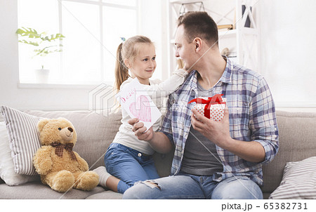 Happy little daughter giving present to her dad 65382731