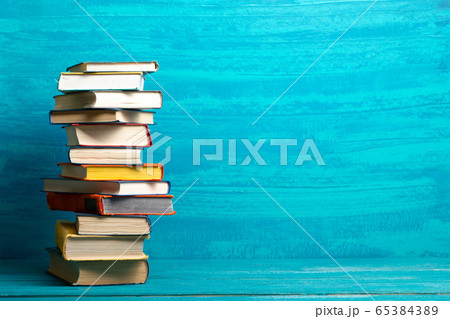 Composition with vintage old hardback books, diary, fanned pages on wooden deck table and abstract background. Books stacking. Back to school. Copy Space. Education background. 65384389