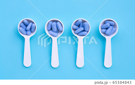 Medical blue pills with white plastic spoon on 65384843