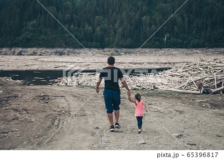 man with baby walk on dry fallen trees on the ground. Sawmill, woodworking industry, construction, firewood, deforestation, environmental disaster 65396817