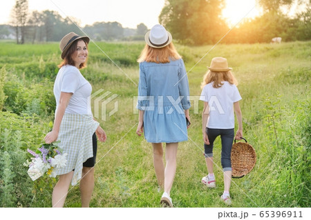 Mother with children two daughters walking along a country road, back view Mother with children two daughters walking along a country road, back view 65396911
