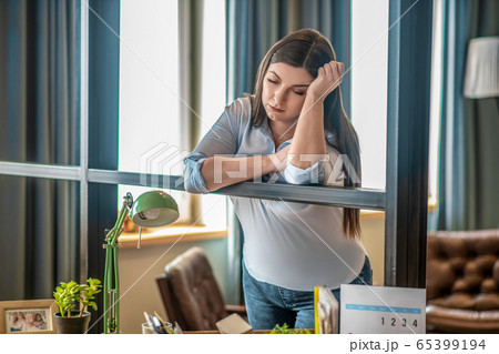 Young woman standing in the room and looking stressed 65399194