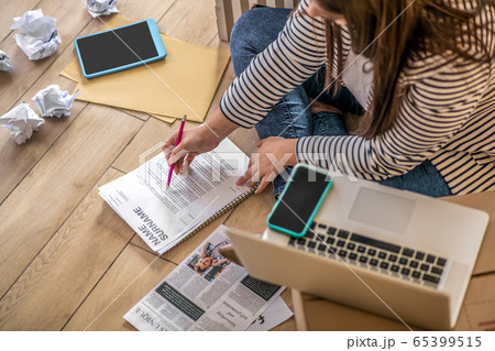 Young woman sitting on the floor and making notes Young woman sitting on the floor and making notes 65399515