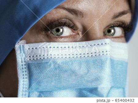 Tired doctor in mask looks at camera. Close up. Selective focus Tired doctor in mask looks at camera. Close up. Selective focus 65400432