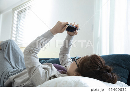 リビングでごろごろする女性（ゲーム画面はピクスタのために作成したダミーです） 65400832