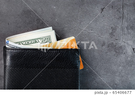 A black wallet with banknotes and a gold A black wallet with banknotes and a gold 65406677